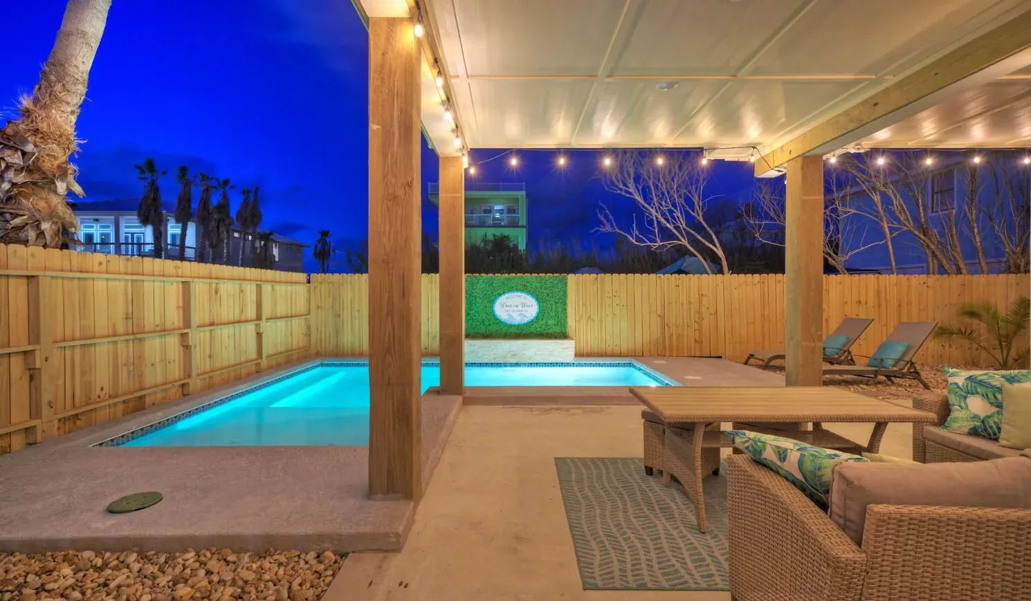A covered patio overlooks a lit swimming pool, with outdoor seating nearby.