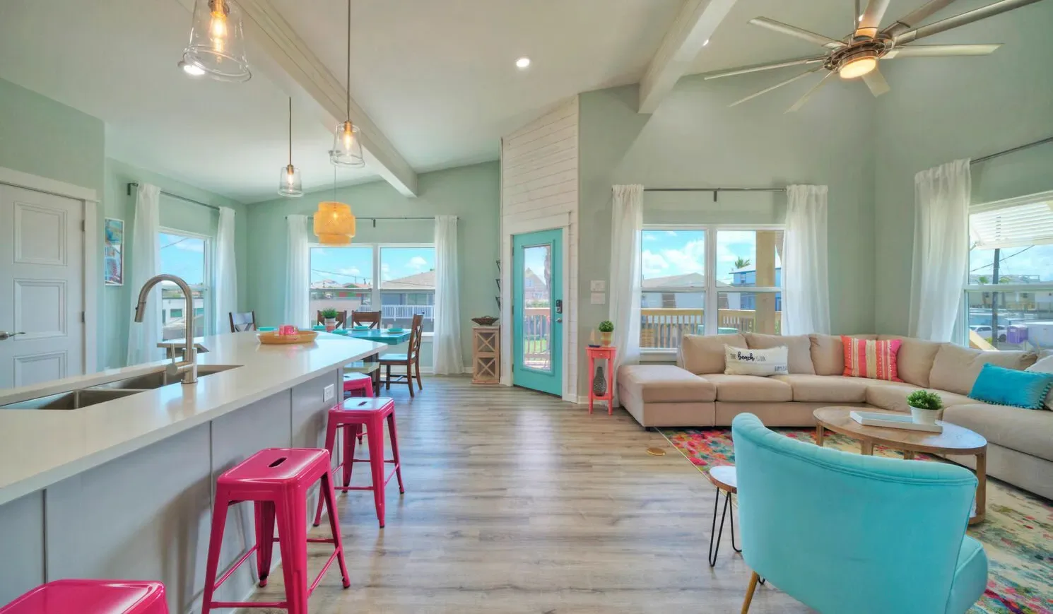 A bright open-plan living room and kitchen with a beige sofa and island seating.