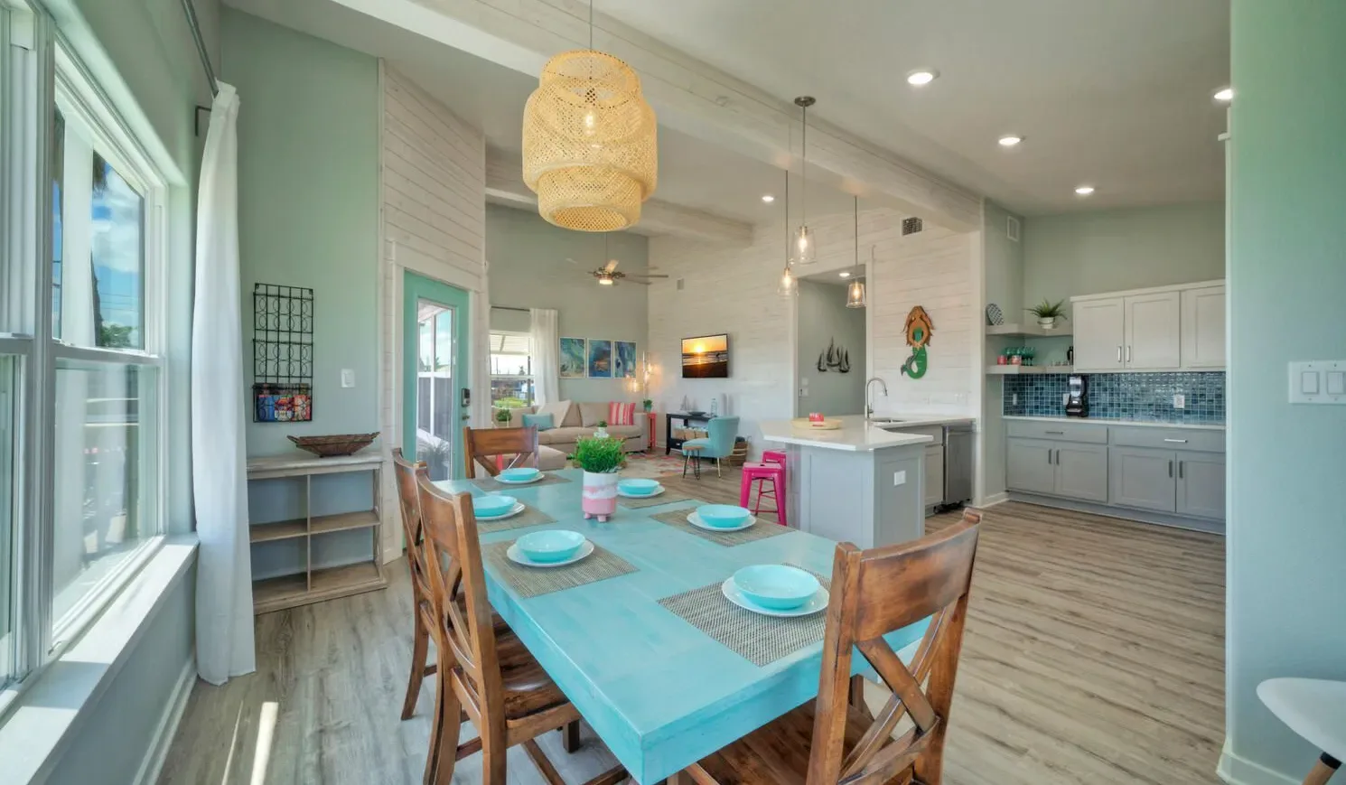 A dining area with a turquoise table beside an open kitchen.