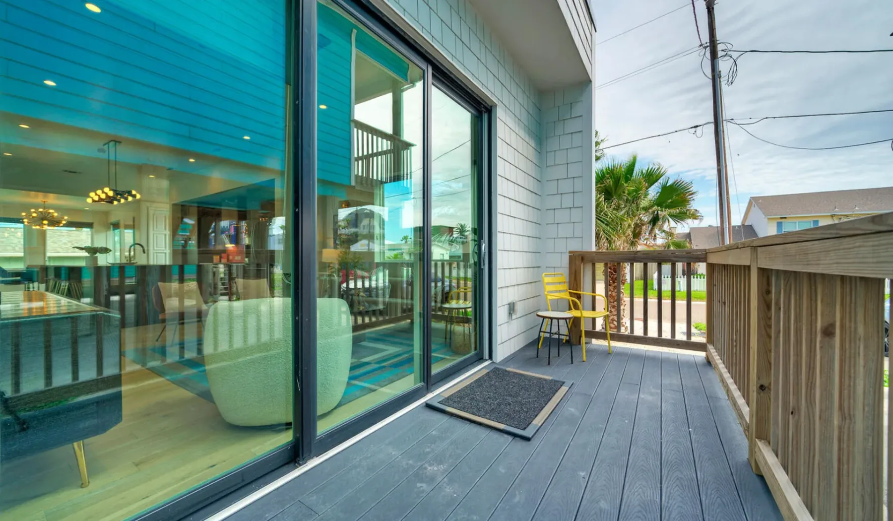 A deck beside large glass doors overlooks a fenced outdoor area.