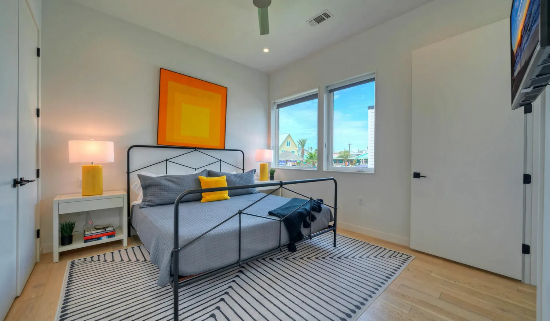 A bright bedroom with a metal-framed bed and striped rug.