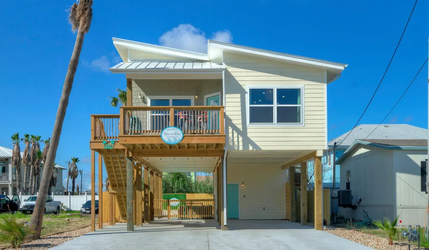 A raised coastal house with a wooden balcony and open space beneath.