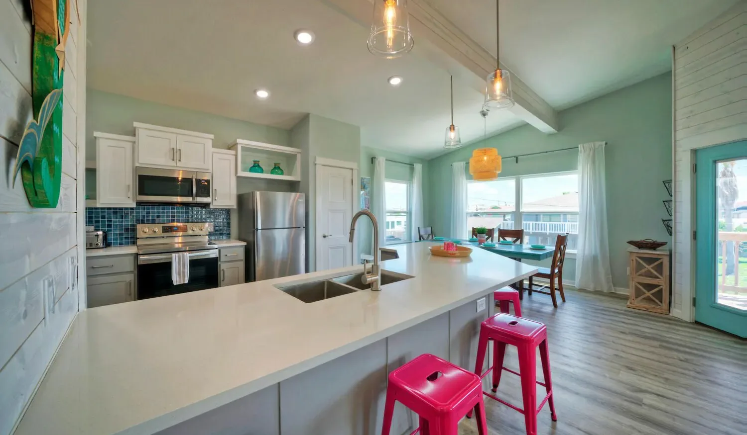 An open kitchen and dining area features a long island and bright windows.