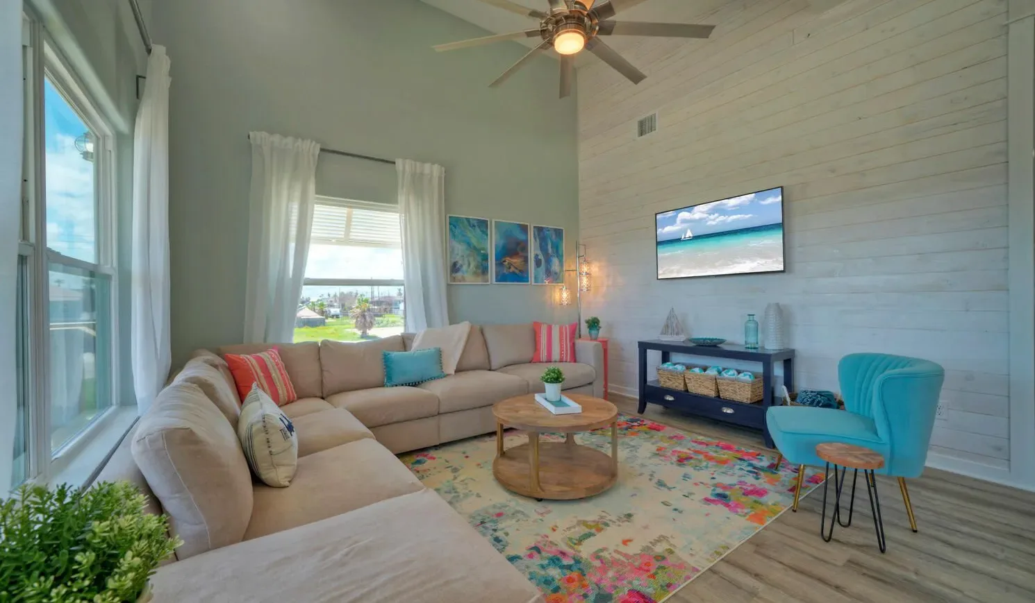 A bright living room with seating, a coffee table, and a television.