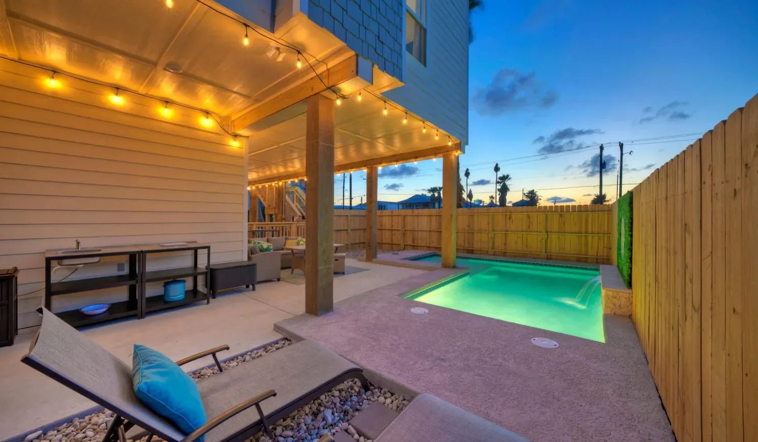 A covered outdoor patio with a small illuminated swimming pool and lounge seating.