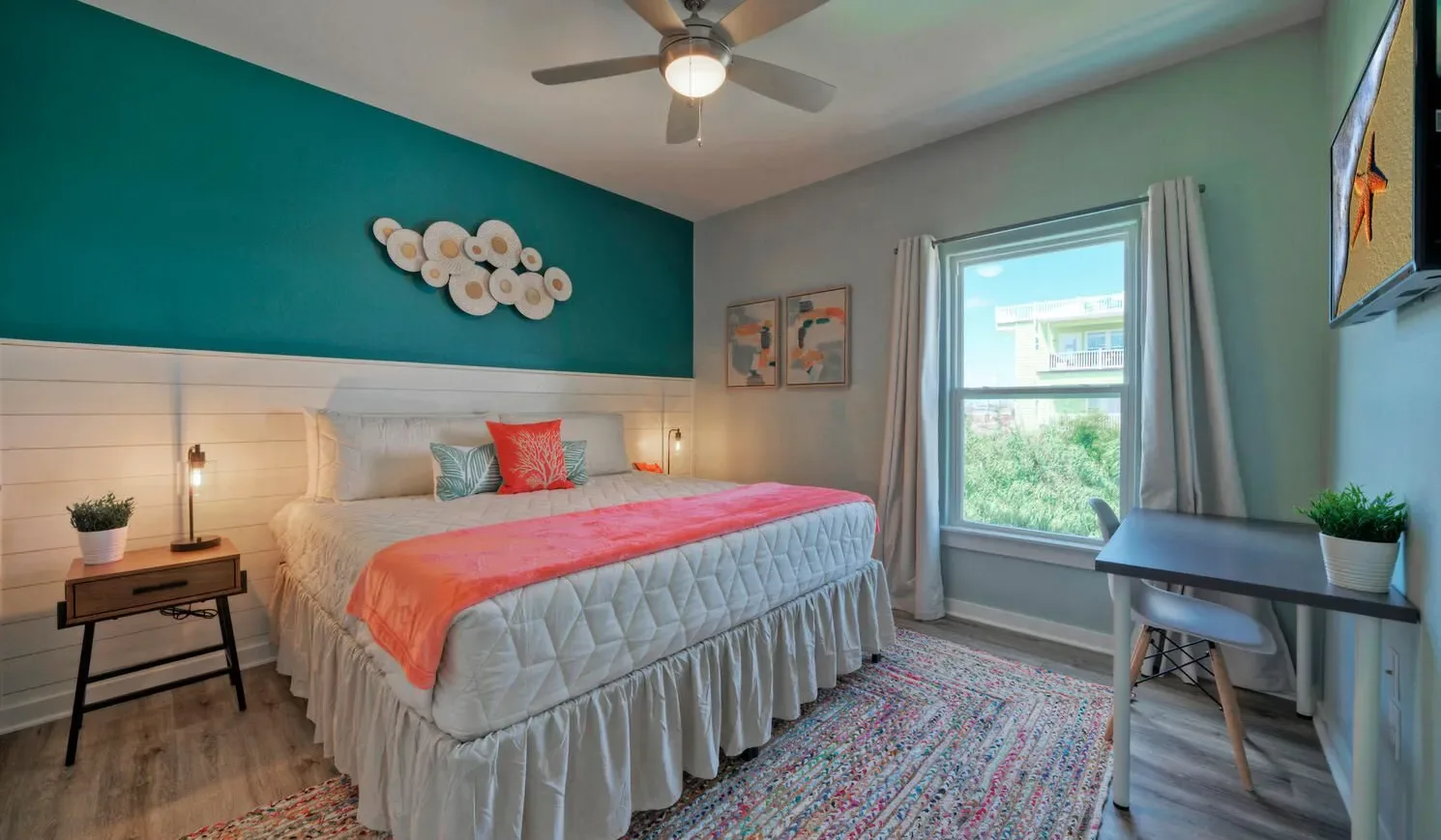 A bedroom with a bed, colorful bedding, and a window.
