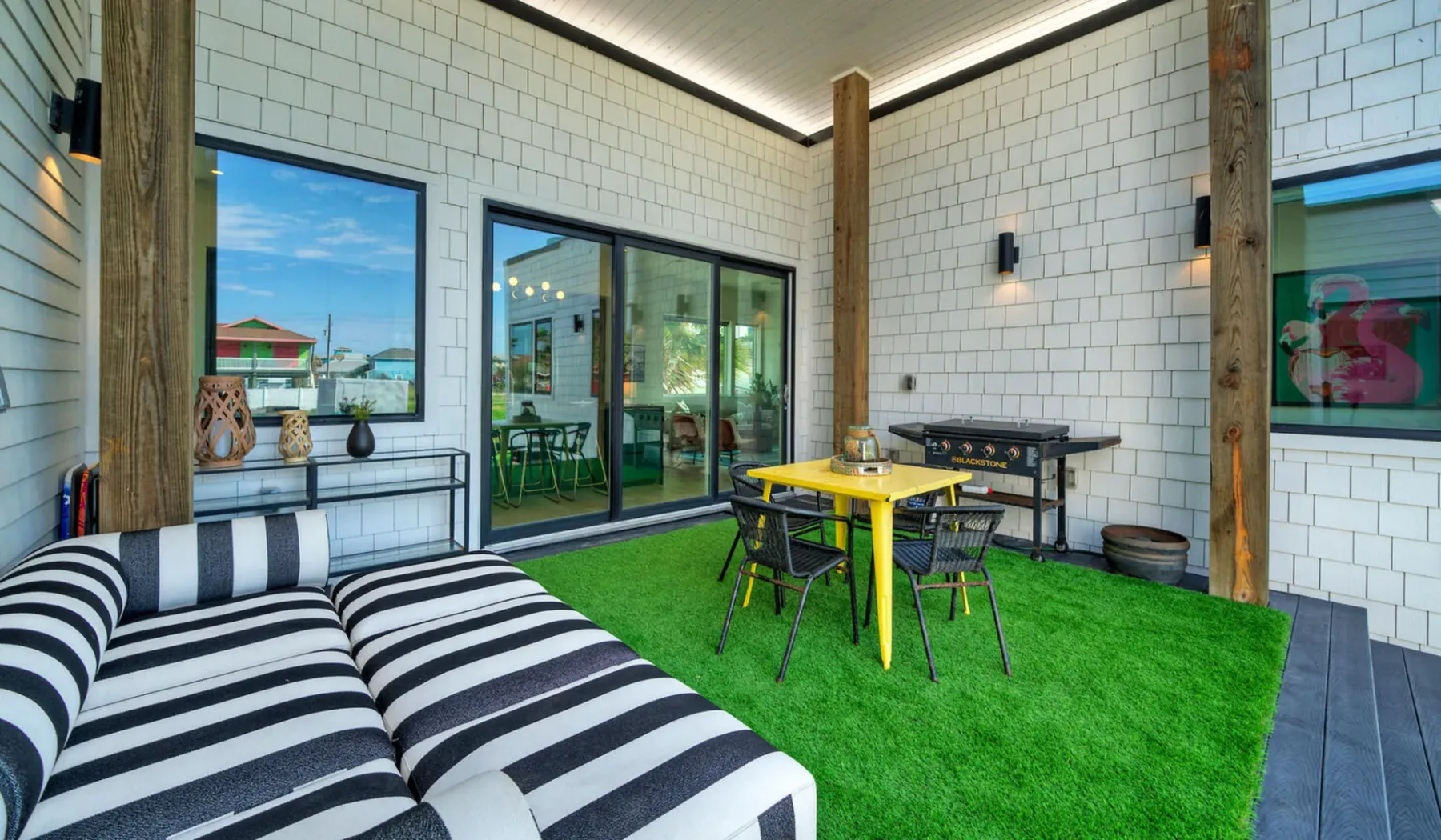 A covered patio with seating, a table, and bright green flooring.