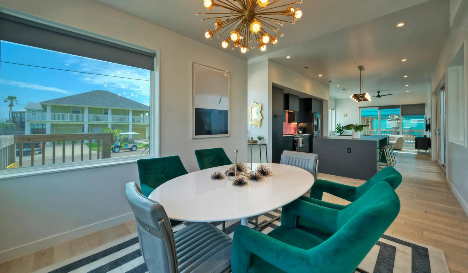 A bright dining and living area has an oval table and teal seating.