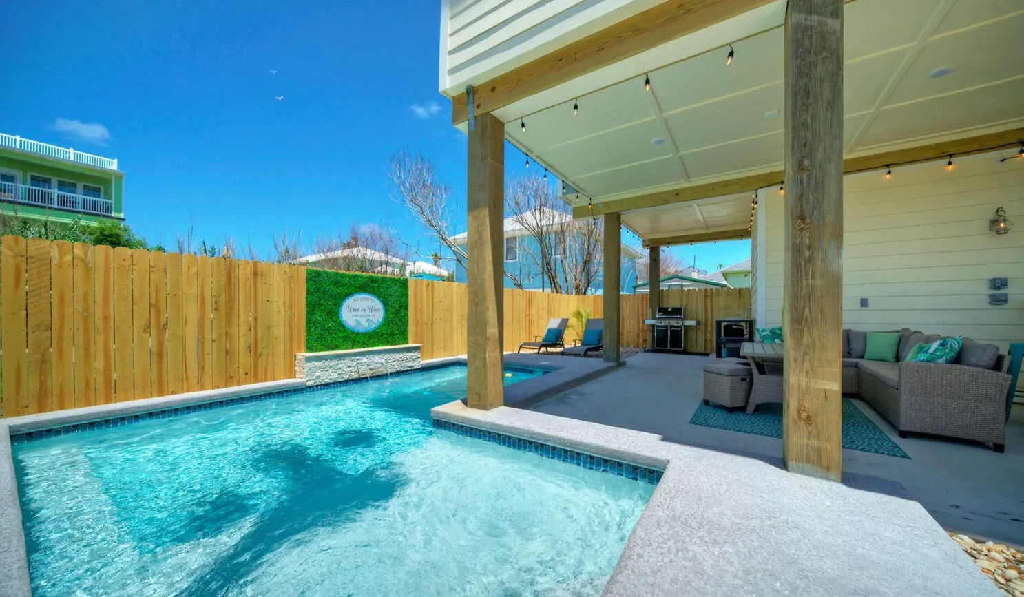 A swimming pool beside a covered patio with outdoor seating.