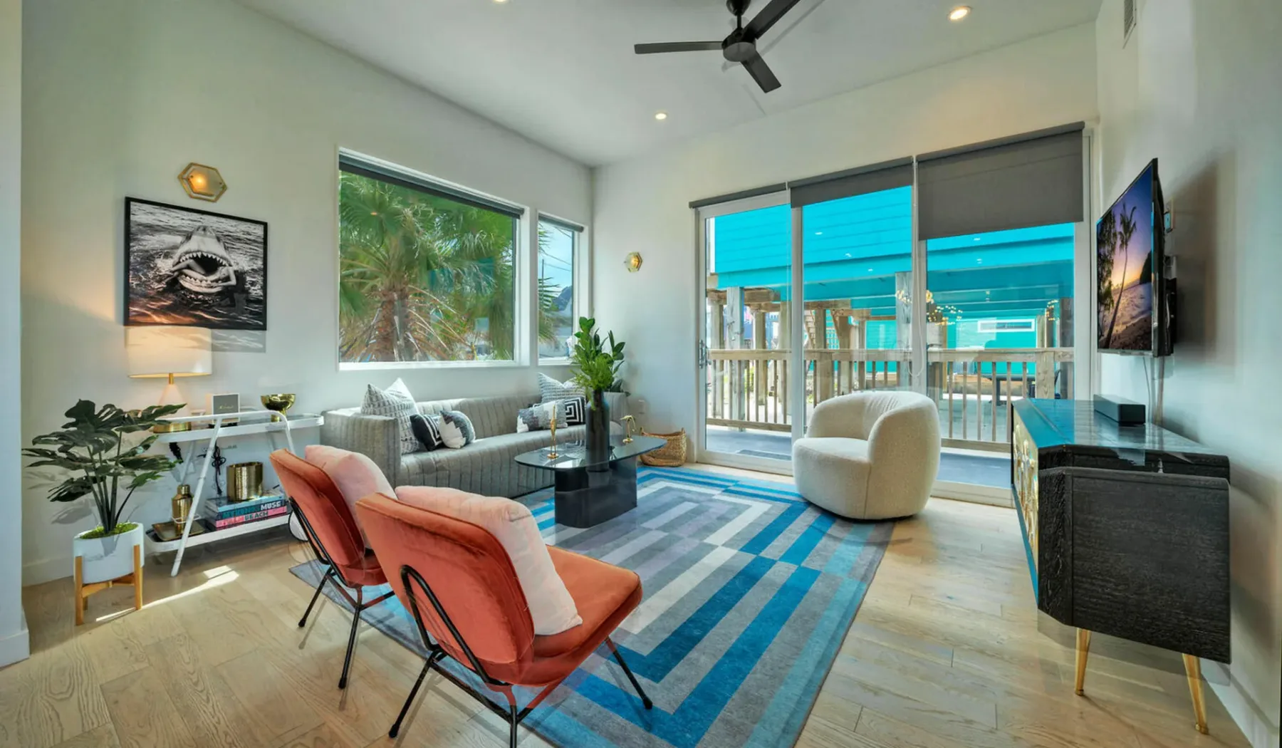 A bright living room with coral seating, a striped rug, and sliding glass doors.