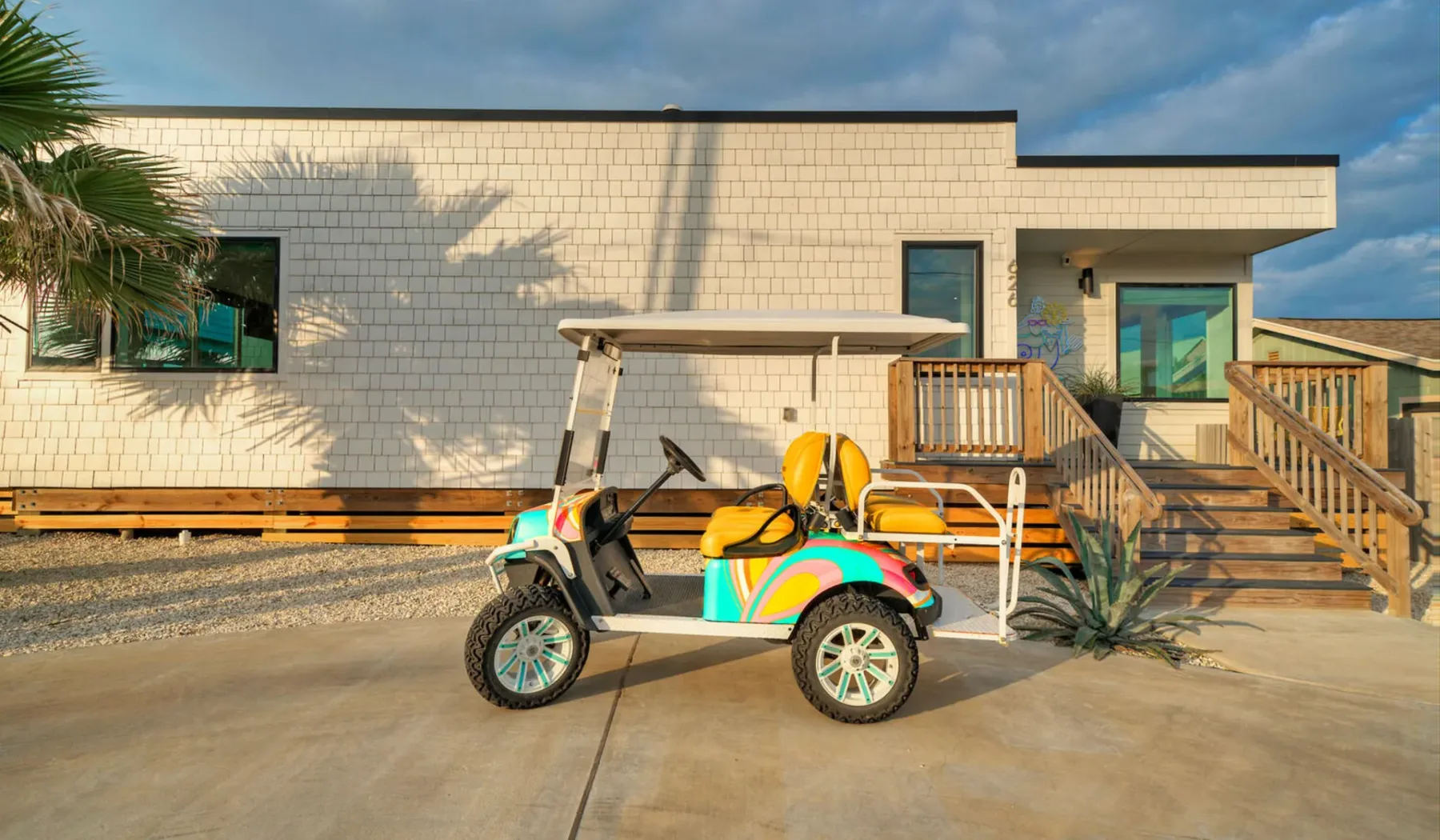 A low modern building with a colorful golf cart parked outside.