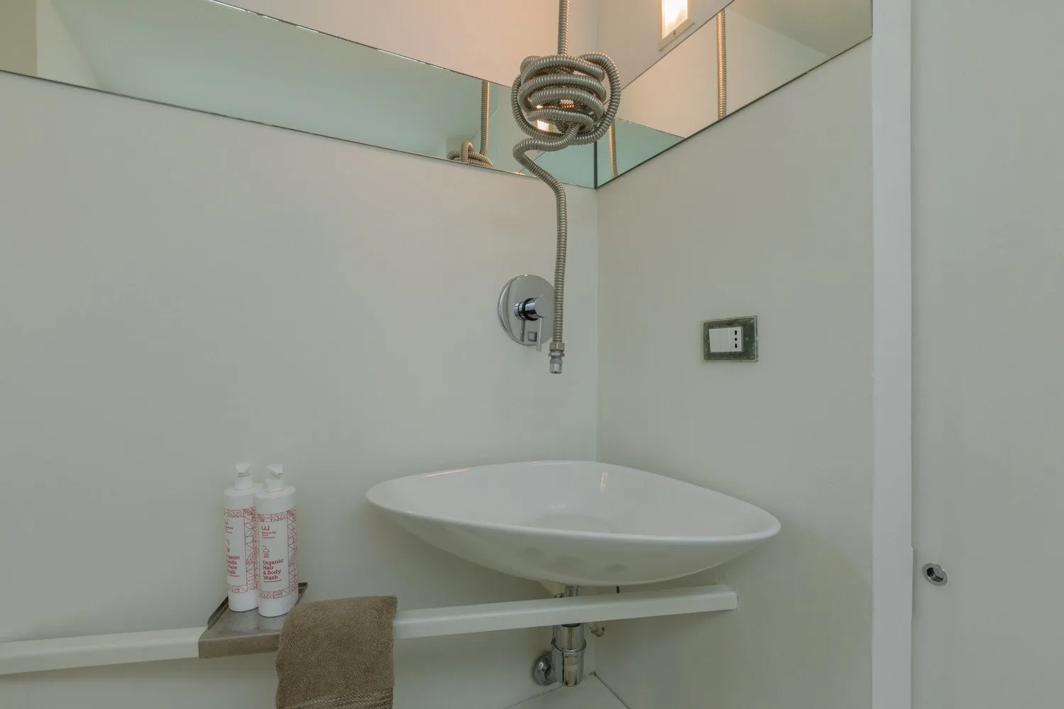 Un lavabo de baño está debajo de una ducha montada en la pared.