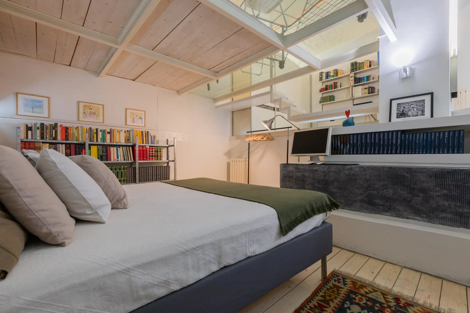 Dormitorio con cama, estanterías de libros y zona de escritorio.