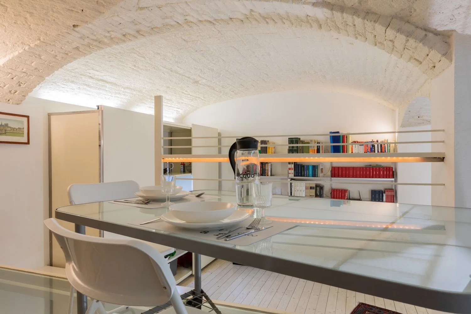 Comedor bajo un techo abovedado de ladrillo, con una mesa y estanterías.