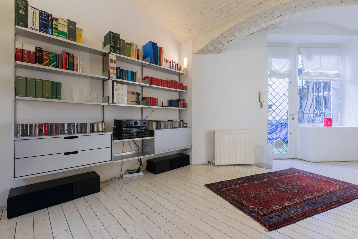 Una sala luminosa con estanterías empotradas y una alfombra estampada.