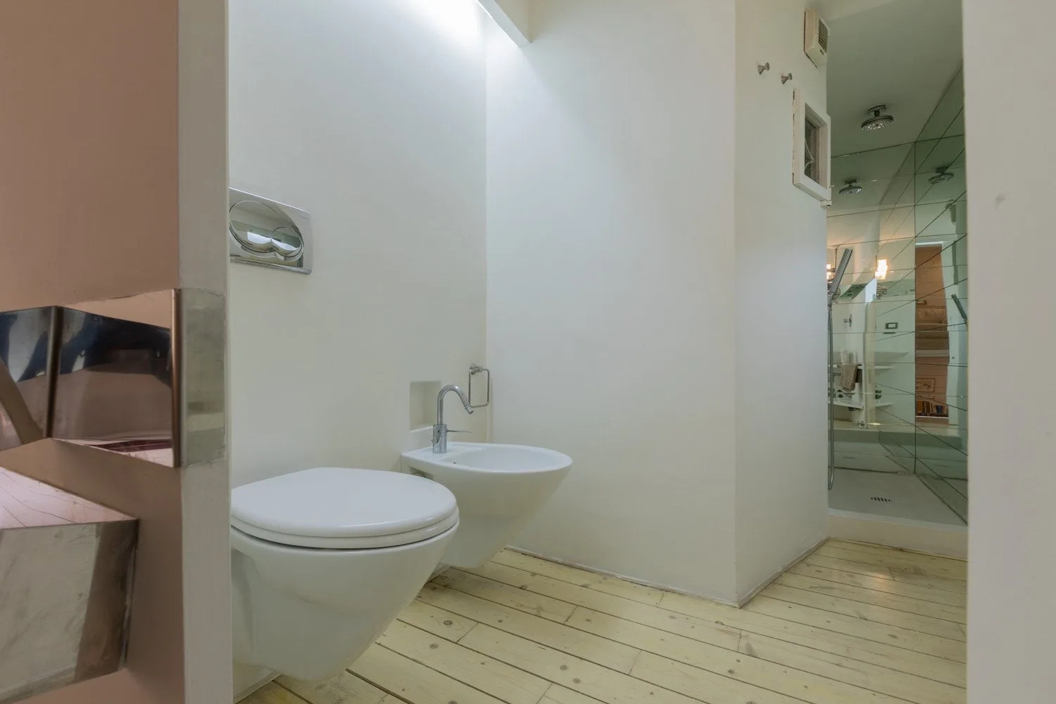 Un baño con inodoro y lavabo junto a una ducha de vidrio.