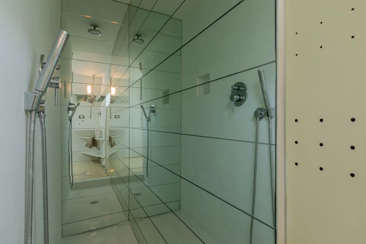 Una ducha con paredes de azulejos, mampara de vidrio y accesorios.