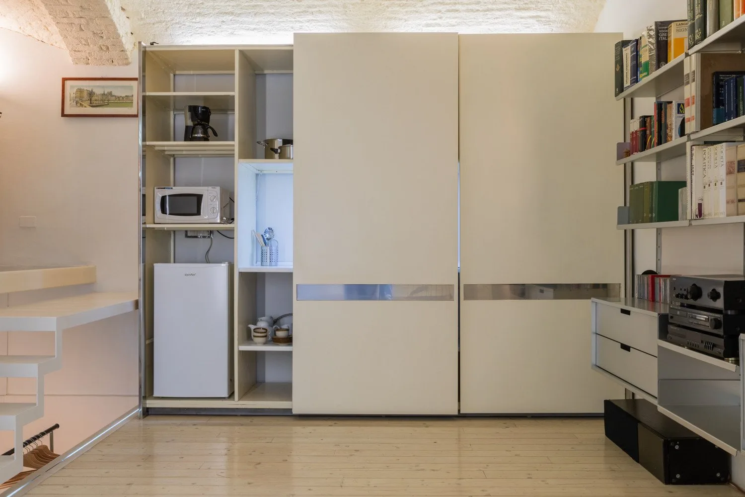 Una pequeña cocina con electrodomésticos integrados y estanterías.