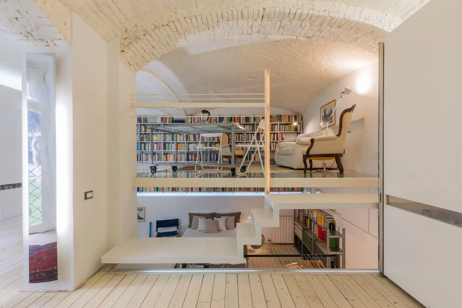 Una biblioteca elevada con estanterías llenas de libros y una pequeña zona de estar.