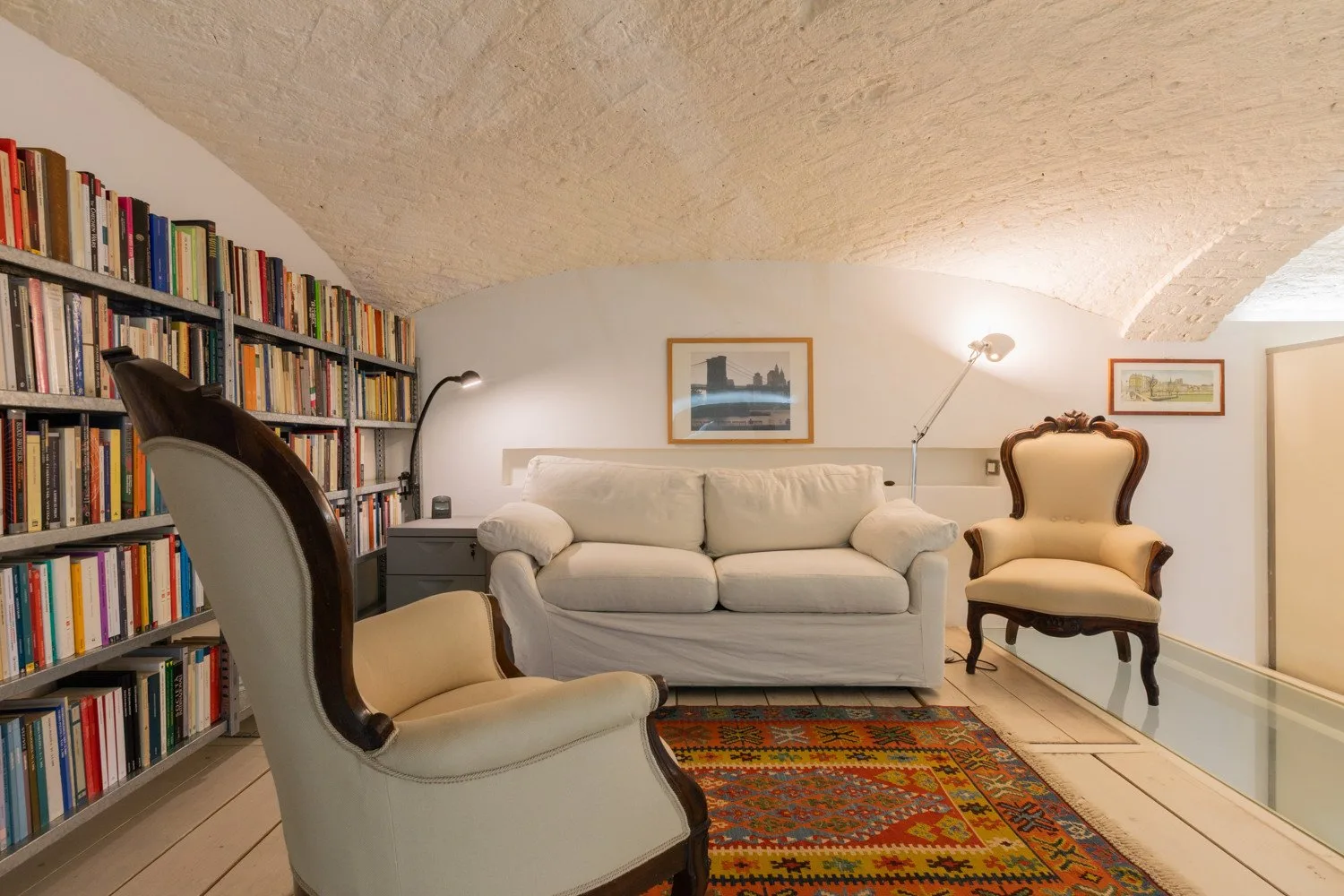 Una sala de estar con un sofá claro, sillones tapizados y una alfombra colorida.