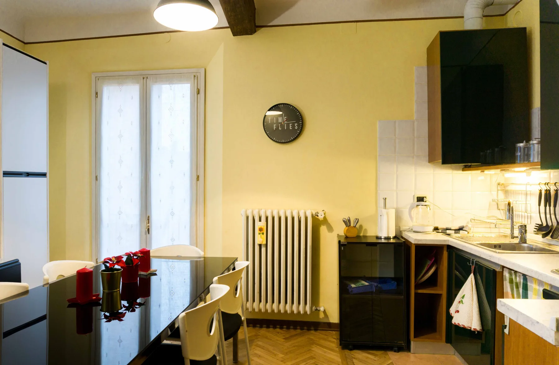 A dining area beside a compact kitchen, with a glass table and white chairs.