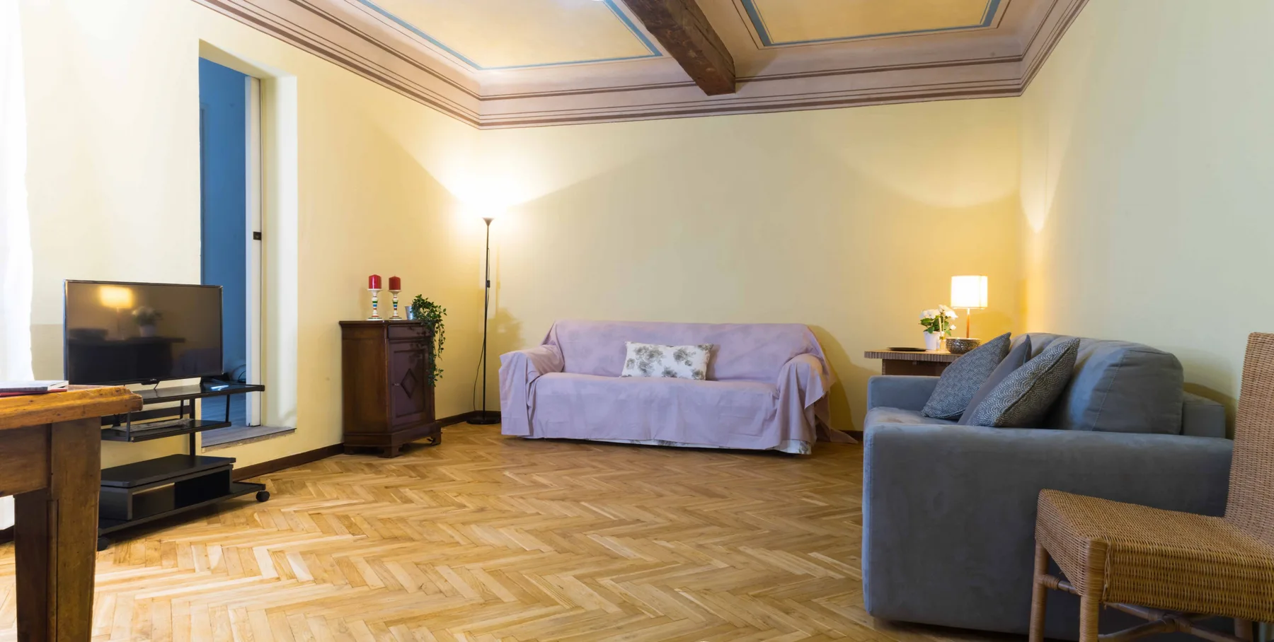 A living room with seating, a television, and parquet flooring.