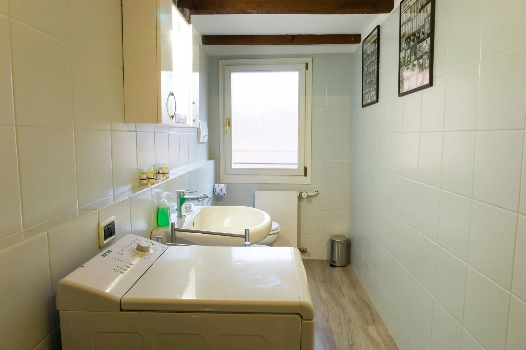 A bright bathroom with a bathtub, washing machine, and window.