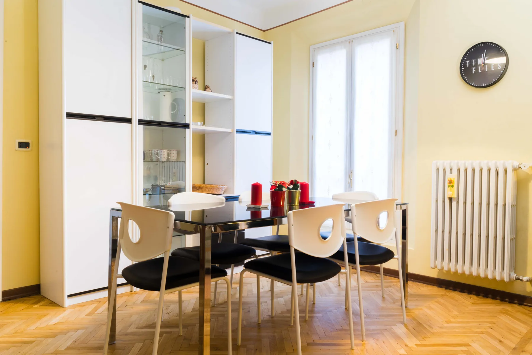 A dining area with a table and chairs beside a bright window.