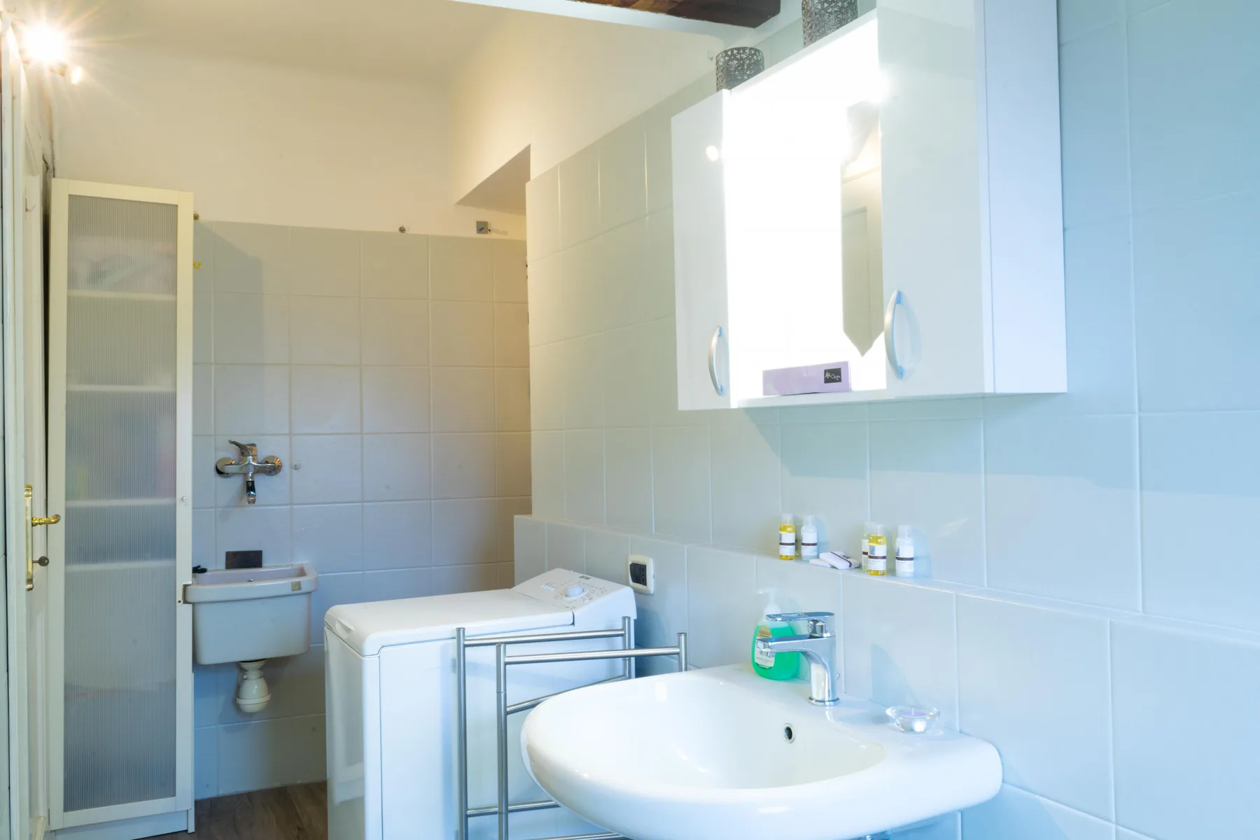 A tiled bathroom with a sink, washing machine, and toilet.