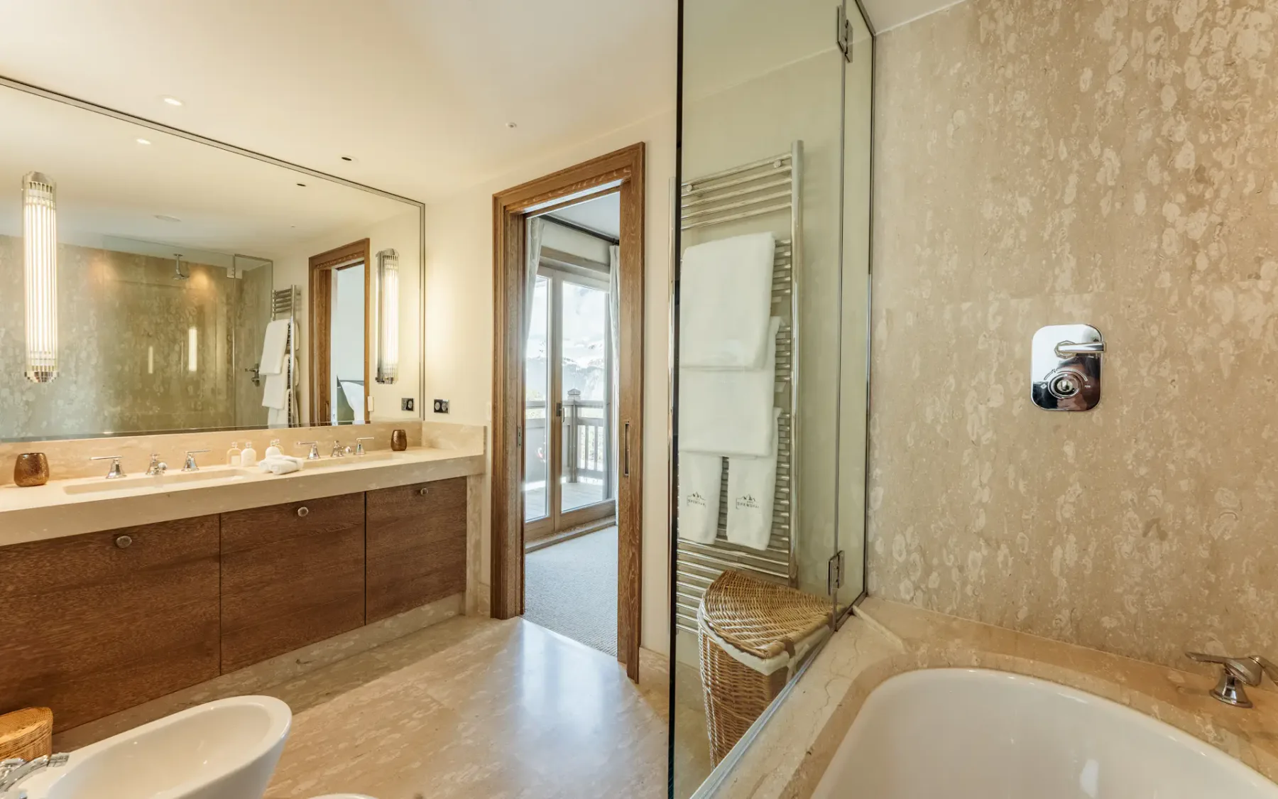 Baño luminoso con un mueble largo, un espejo grande, una ducha de cristal y una bañera.
