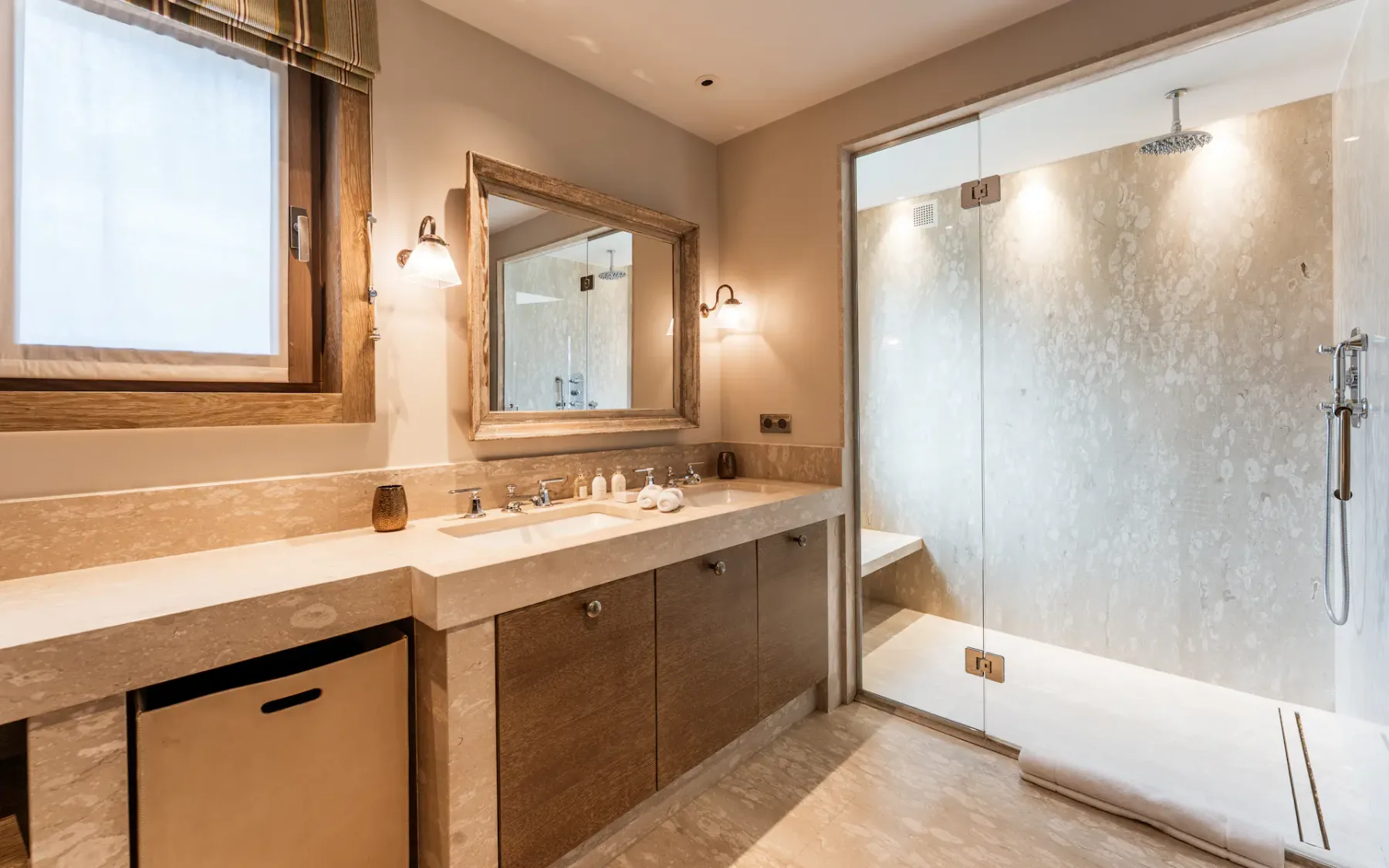 Un baño con un tocador largo, un espejo y una ducha de cristal.