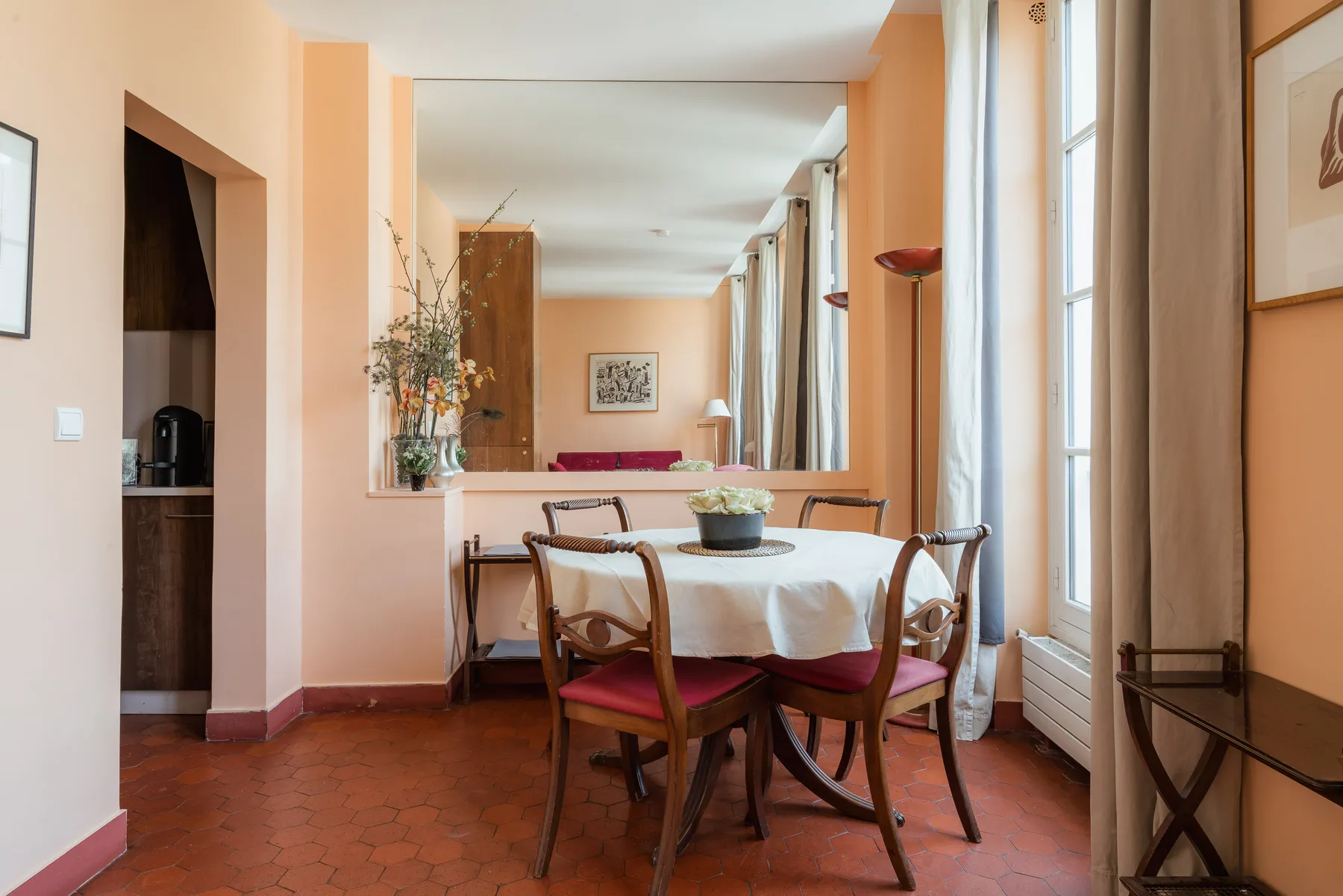 A dining area with a table, chairs, and tall windows.