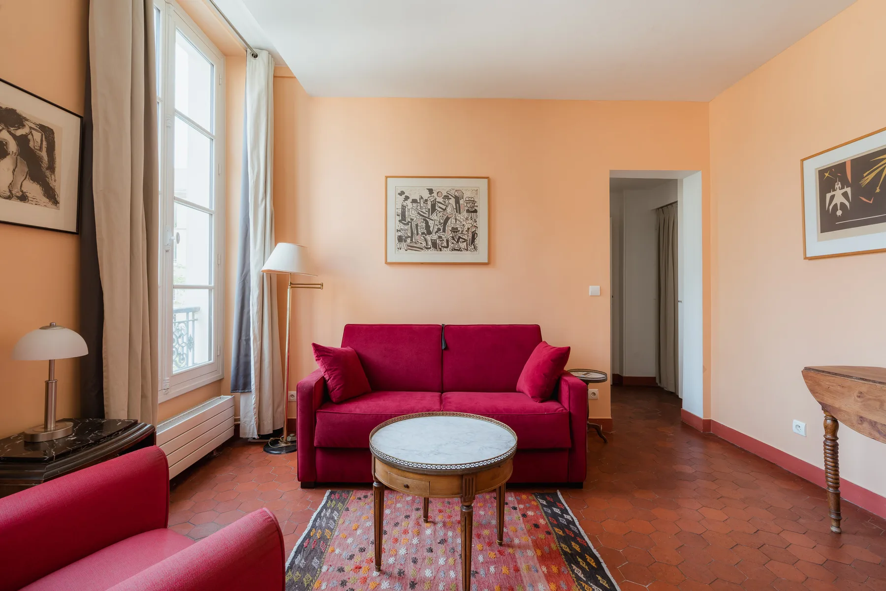A peach-colored living room with red seating and a small round table.