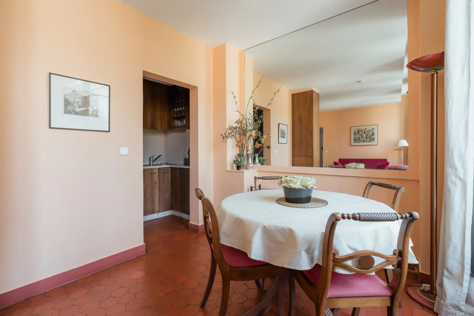 A dining area with a round table set beside a large wall mirror.