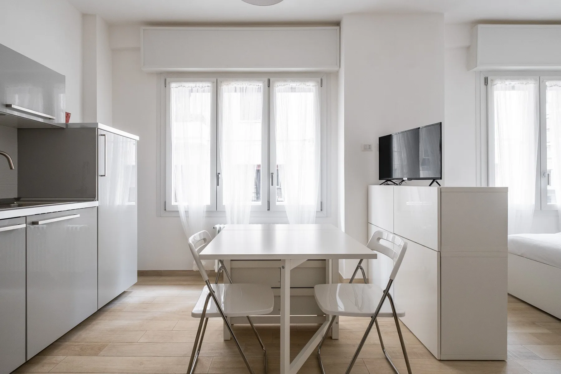 A bright dining area with a table and chairs beside a compact kitchen.
