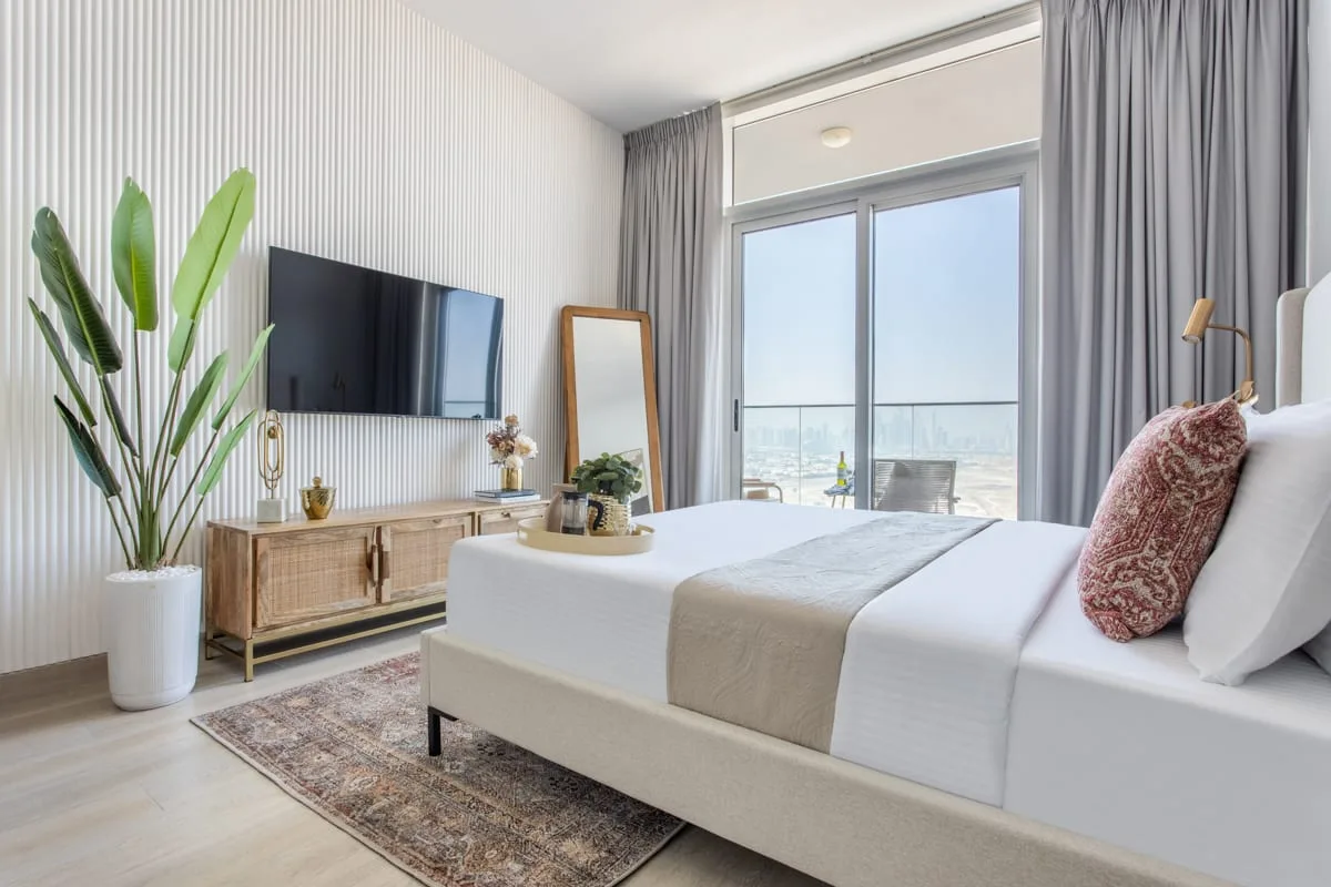 Un dormitorio luminoso con una cama bien hecha junto a grandes ventanales.