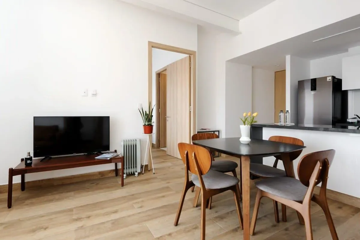 A dining area with a wooden table and chairs beside a television.