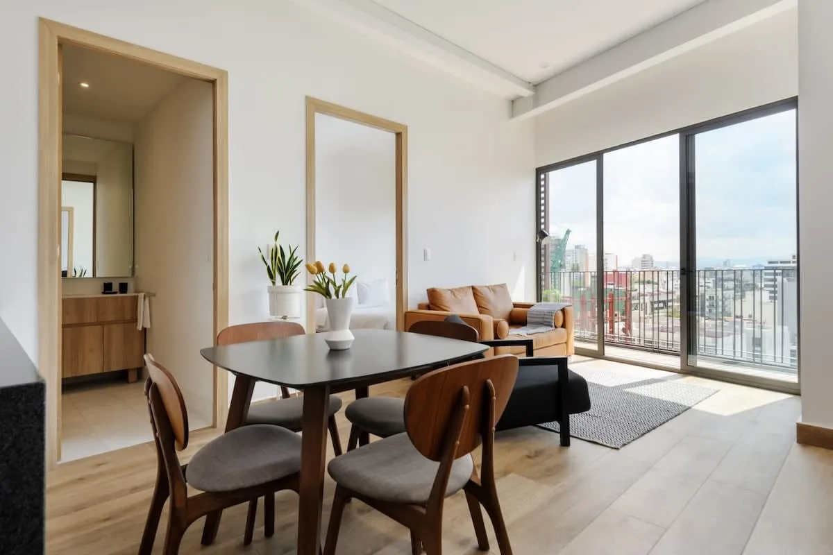 A bright living and dining area opens onto a balcony through large glass doors.