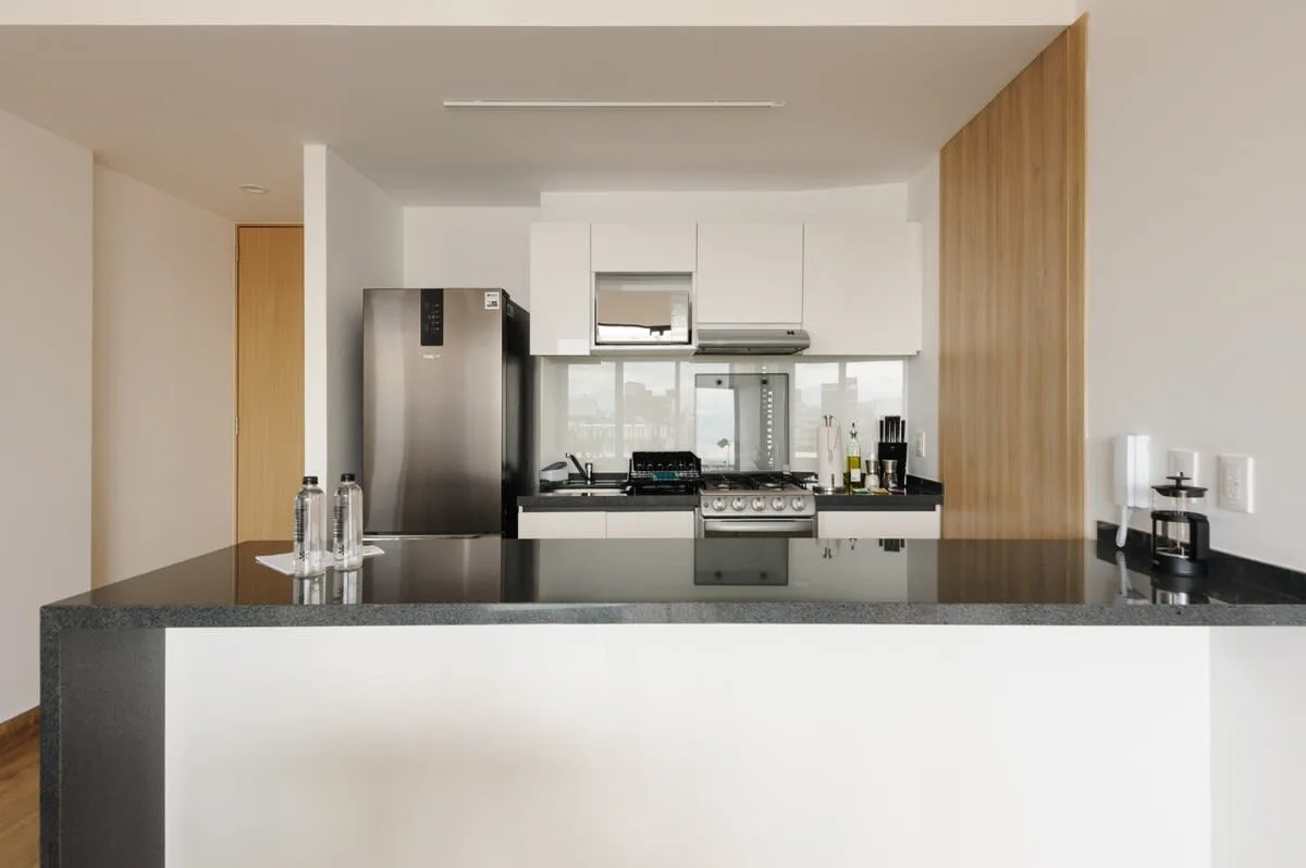 A modern kitchen with white cabinets and a dark countertop.