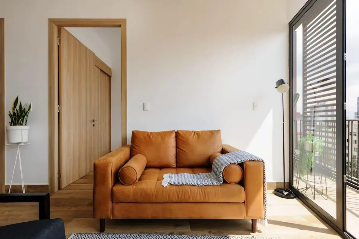 A living room with a brown sofa beside tall glass doors.