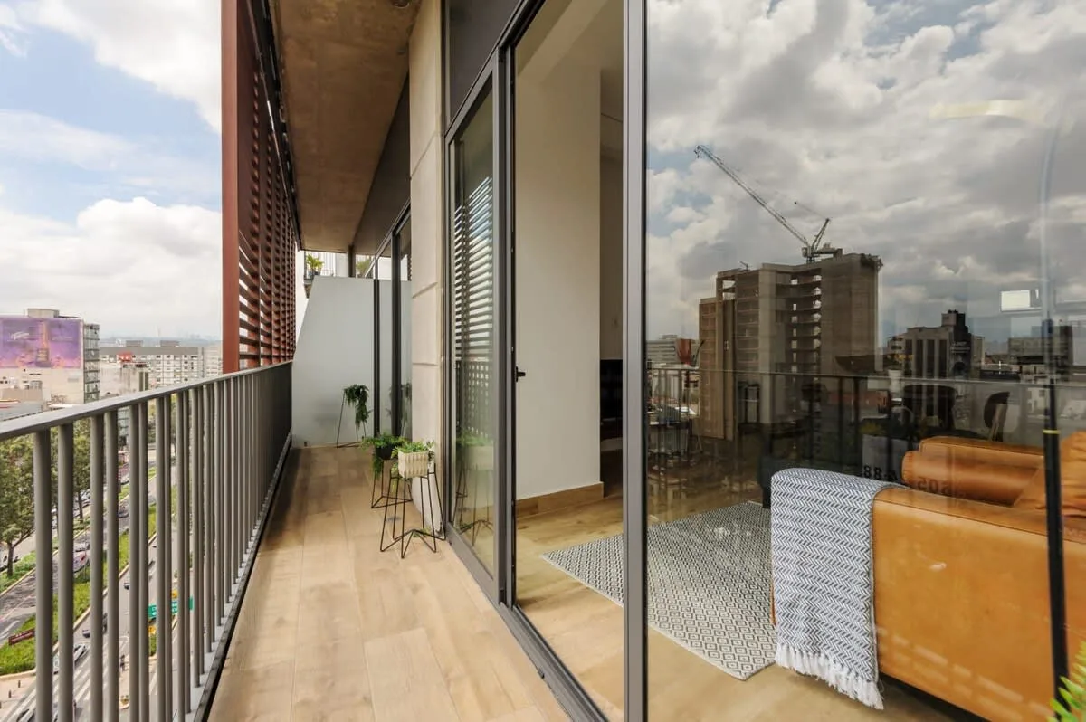 A balcony beside glass doors overlooks nearby buildings and the city.