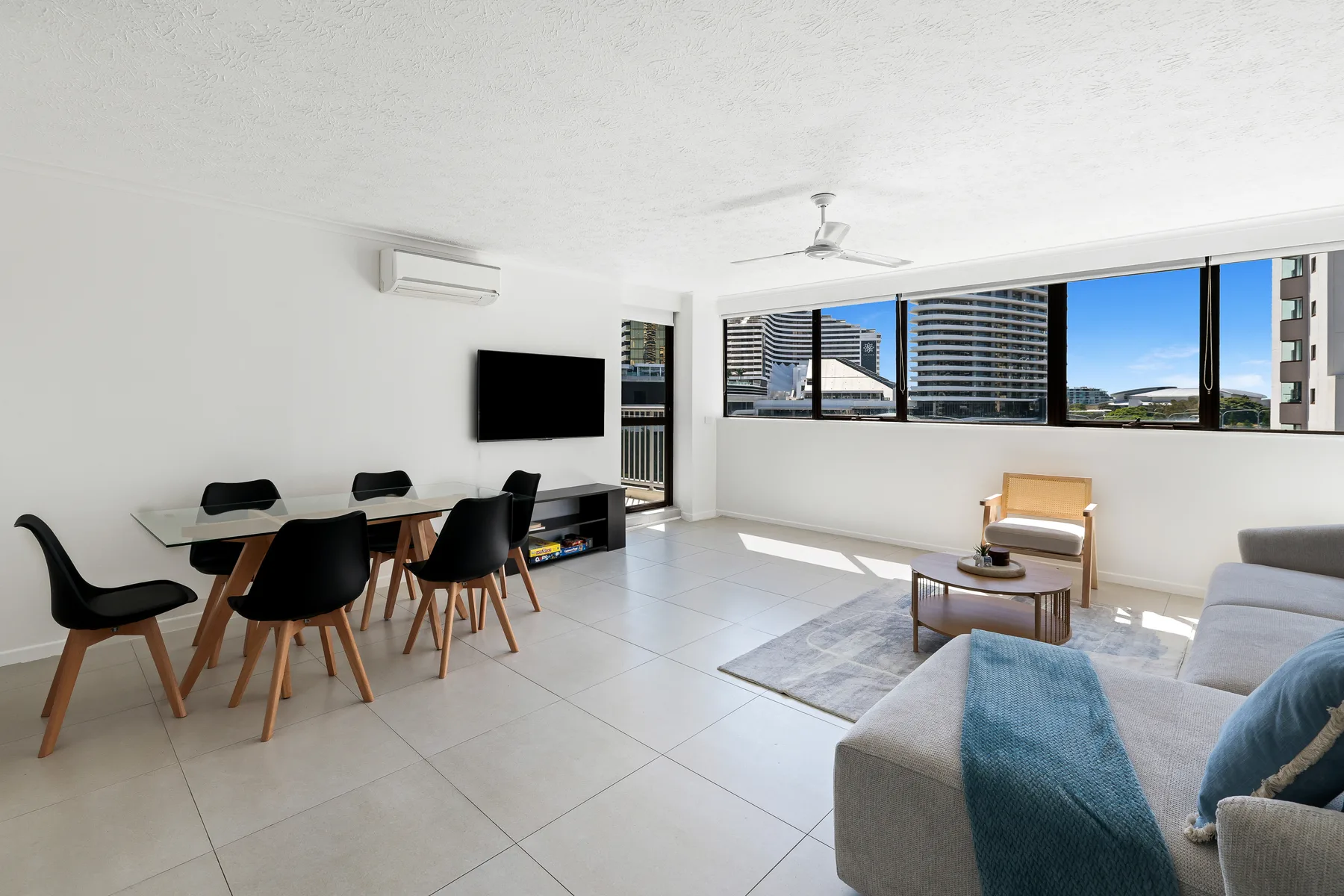 A bright living room with a dining table, seating, and large windows.