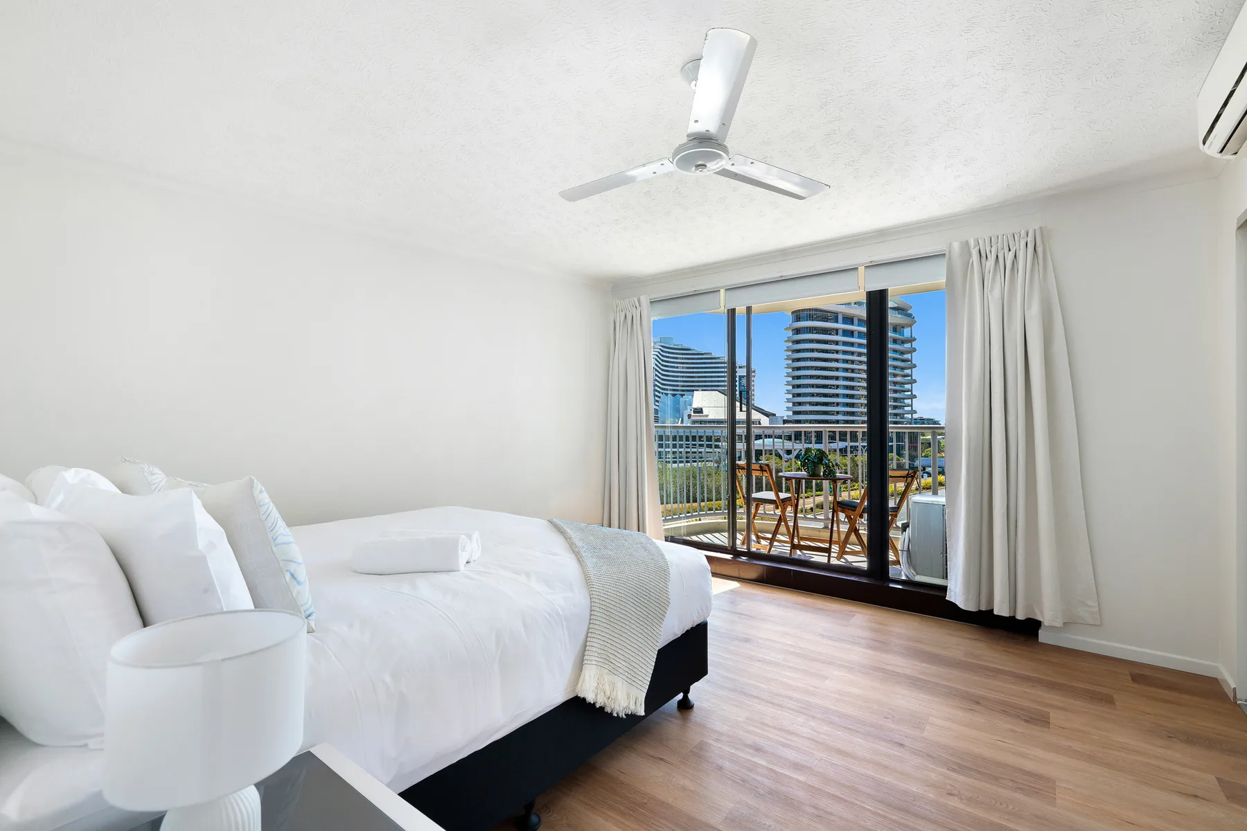A bright bedroom with a bed and sliding glass doors opening onto a balcony.