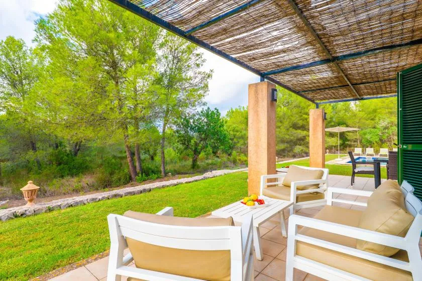 A shaded outdoor seating area opens onto a green garden.