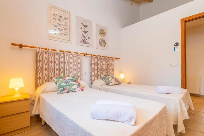 A bedroom with two beds, patterned curtains, and framed artwork on the wall.