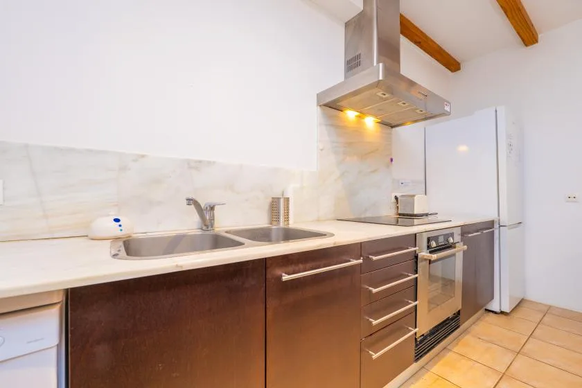 A modern kitchen with a long counter, sink, and built-in oven.