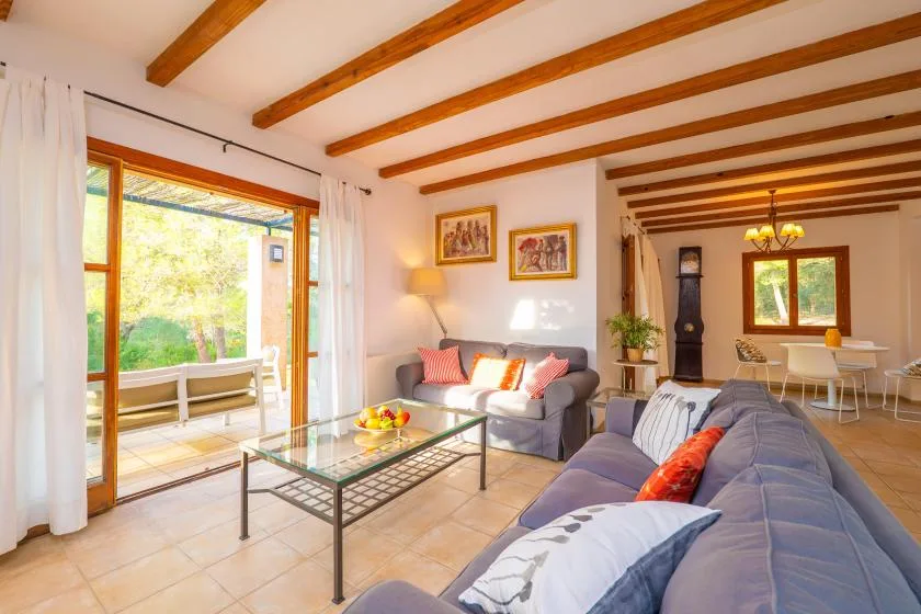 A living room with seating around a glass coffee table and doors opening to a patio.