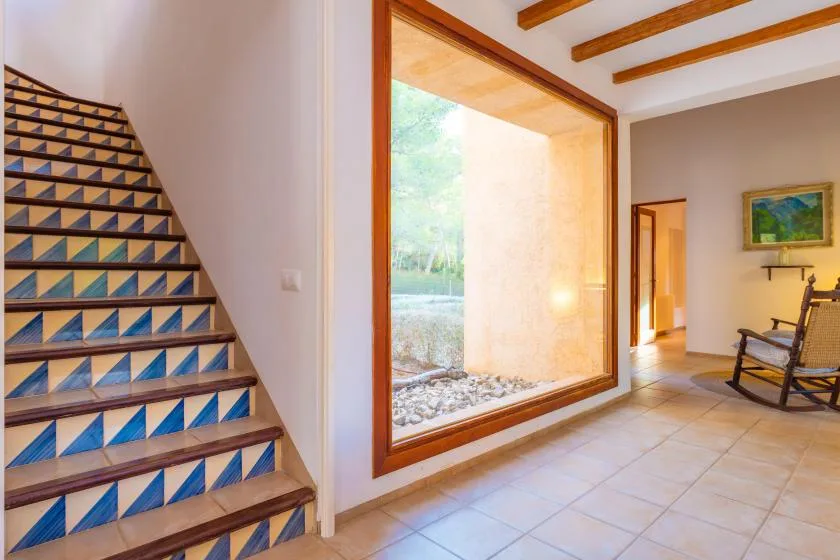 A tiled staircase and a large window brighten this interior hallway.