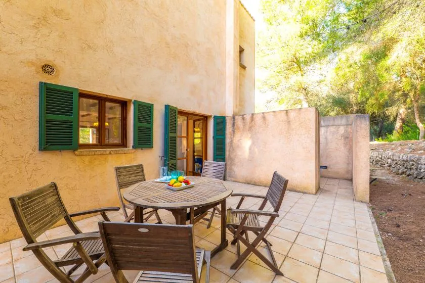 An outdoor patio with a round table and wooden seating beside a stucco wall.
