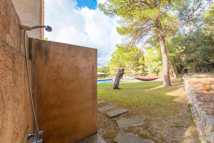 An outdoor shower opens onto a grassy yard with trees and a hammock.